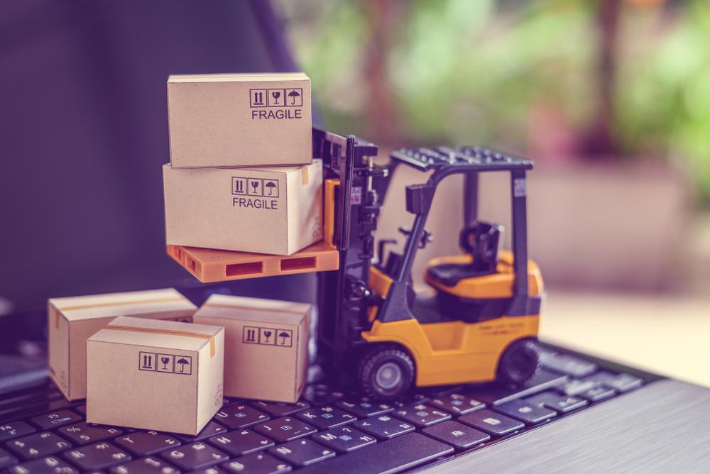 stock image of mini forklift sitting on laptop and lifting boxes