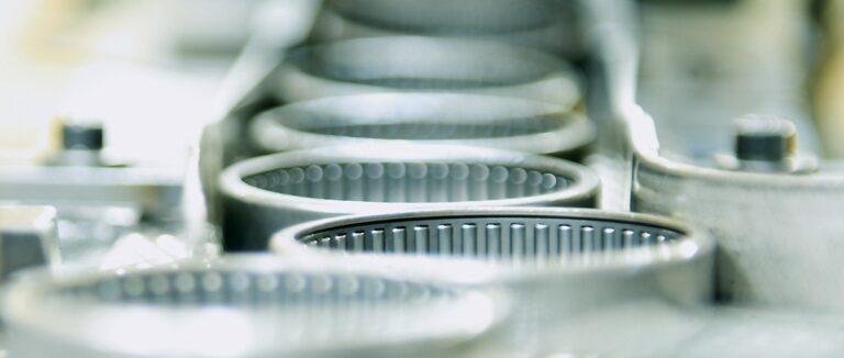 Manufactured needle bearings move in a linear fashion along a conveyor.